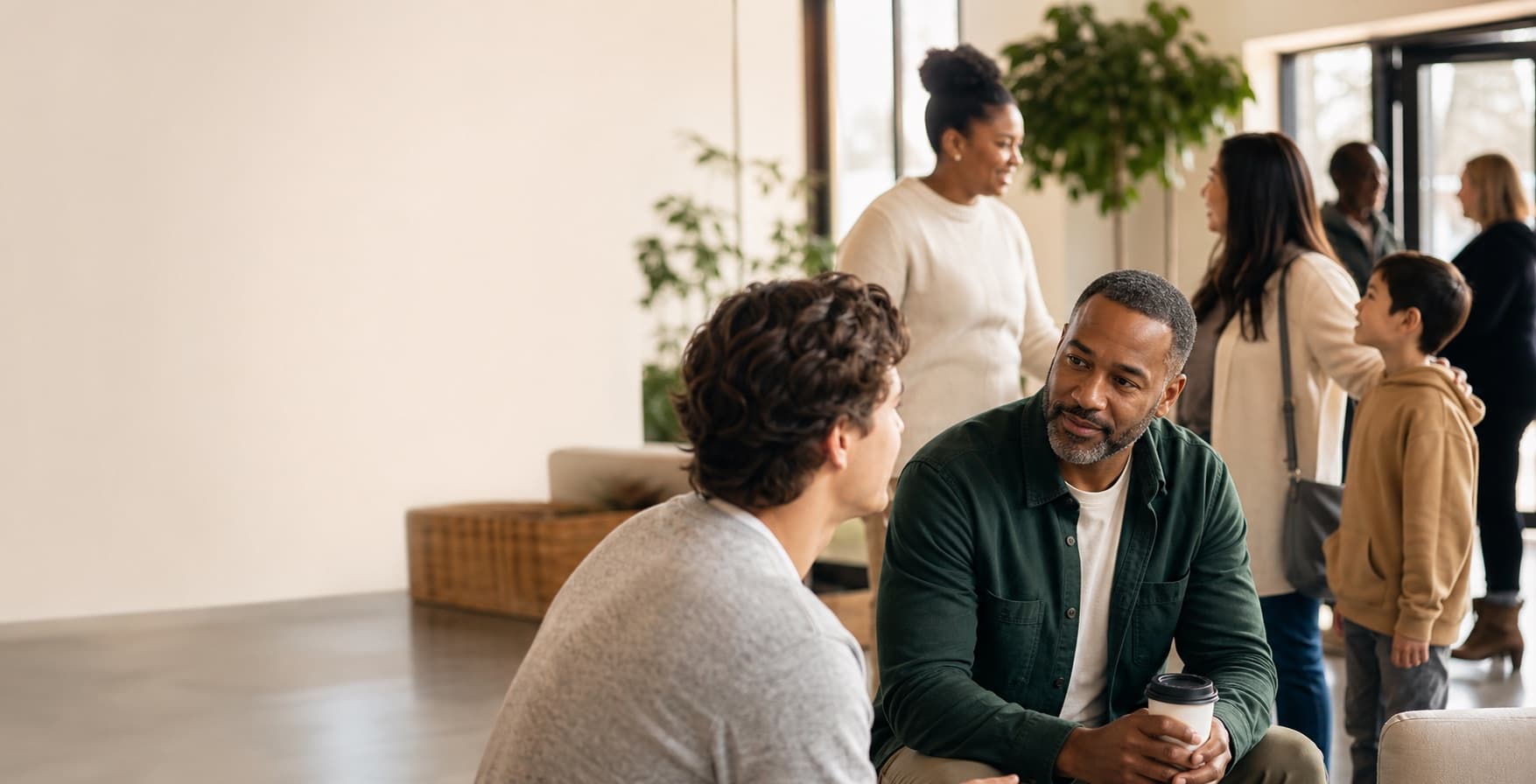Pastor listening warmly to people in a church lobby after a Sunday gathering